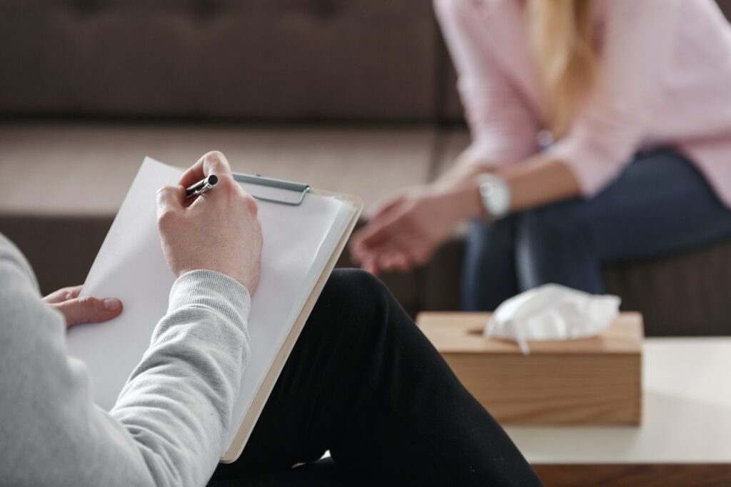 Close-up of therapist hand writing notes during a counseling ses